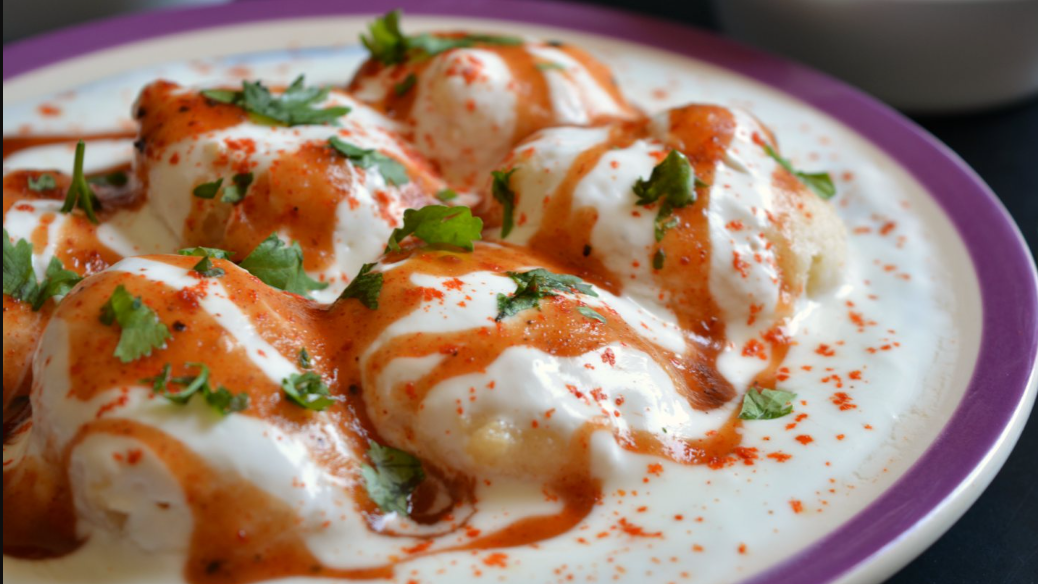 Dahi Vada, also known as Dahi Bhalla, is a popular Indian snack made with lentil dumplings soaked in yogurt and topped with various chutneys and spices